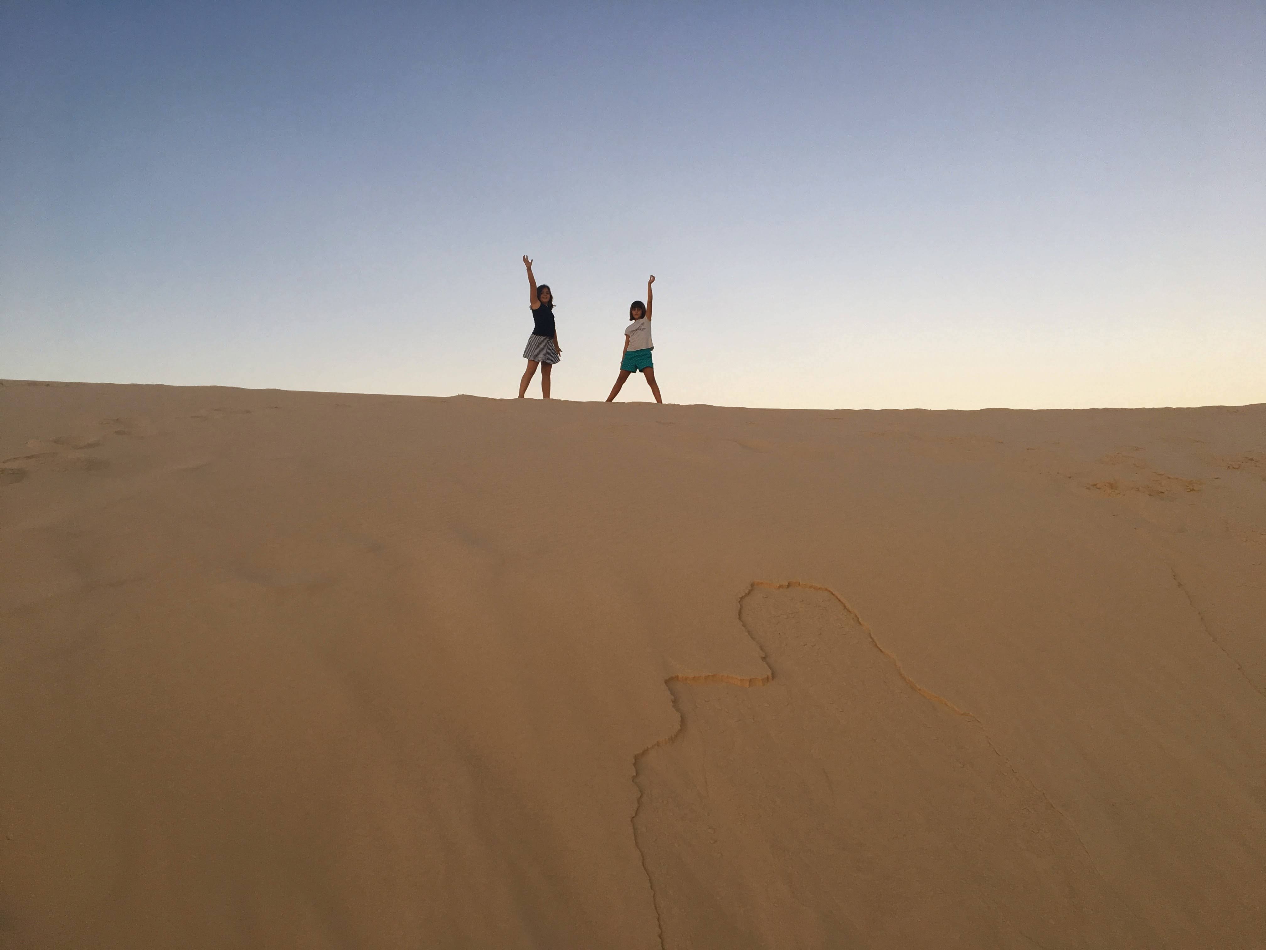 Girls on the dune at sunset