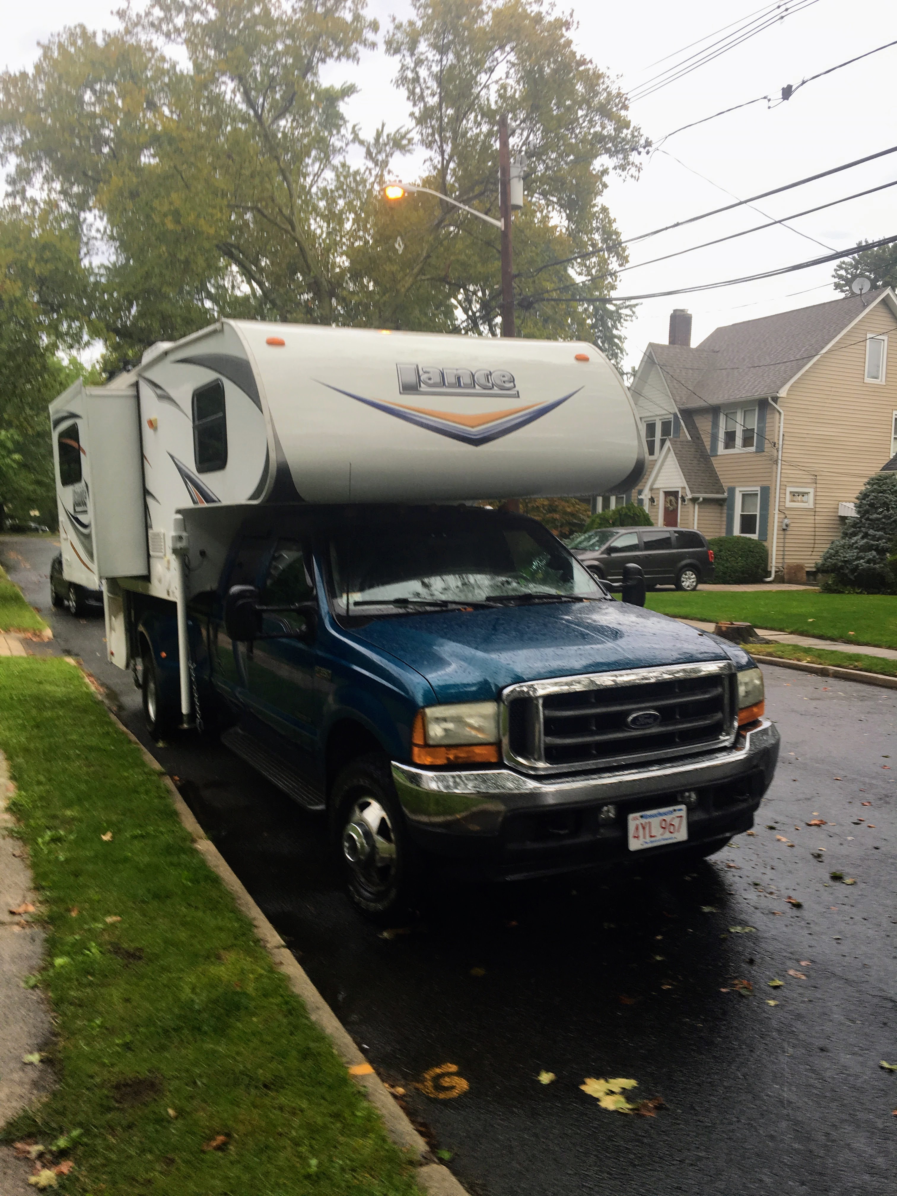 Ford truck with Lance camper parked on a suburban street
